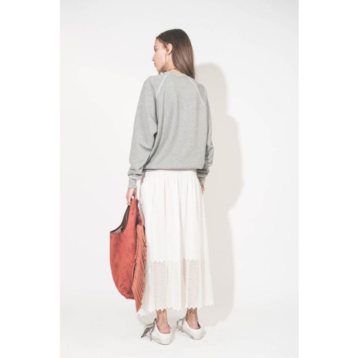 Jupe longue en coton et nid d'abeille placé sur le bas de la jupe blanche The Canary Skirt The Great. Portée de dos avec un sweat-shirt gris chiné College The Great et des sneakers Super Star sabot Golden Goose. Cabas à franges en cuir Terracotta Paco Jér