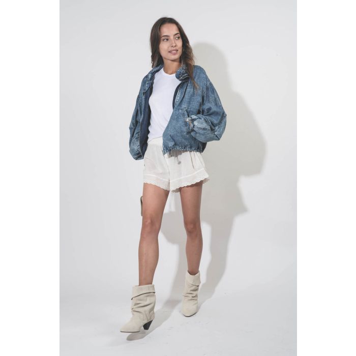 Short court en dentelle et voile de coton blanc Eyelet The Great. Porté avec un blouson bleu délavé.