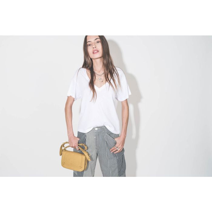 Tee-shirt manches courte col V en coton blanc The Great. Porté avec un pantalon cargo à rayures bleues Railroad R13 et un sac en cuir jaune Mimosa Pepito S Jérôme Dreyfuss. Collier Maria Black et Pascale Monvoisin, bagues en argent Mikuta.