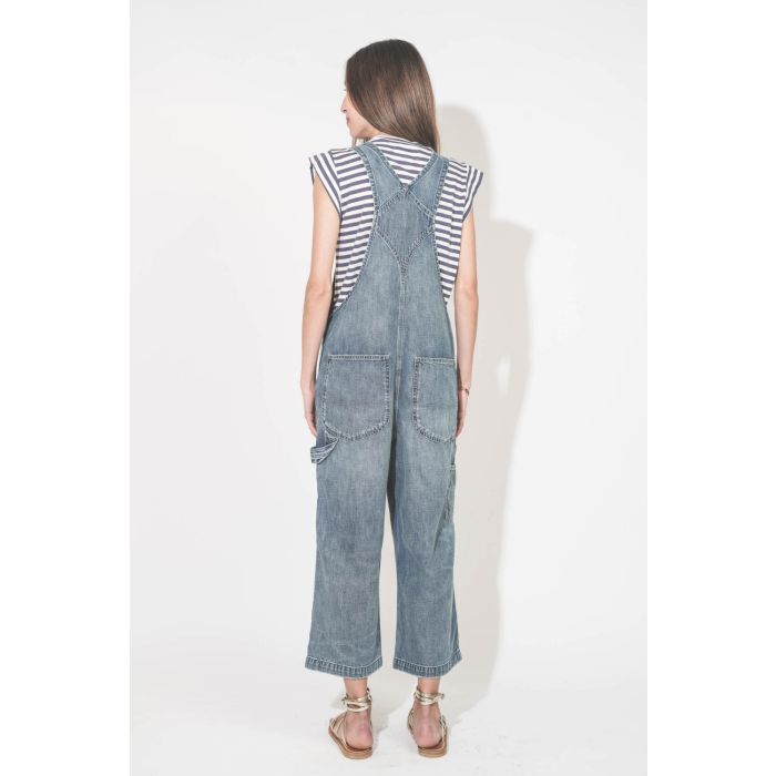 Tee-shirt col rond manches raccourcies à rayures bleu et blanche vinatge Peak Shoulder The Great. Porté de dos avec une salopette en jean bleu Denimist et des sandales en cuir doré Zenobie K.Jacques St-Tropez. 