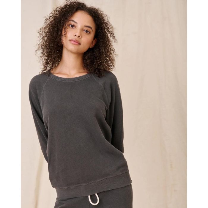 Sweatshirt College en coton noir délavé The Great, porté de face avec un bas de jogging Crop de la même couleur et de la même marque. Détail du sweatshirt effet usé.