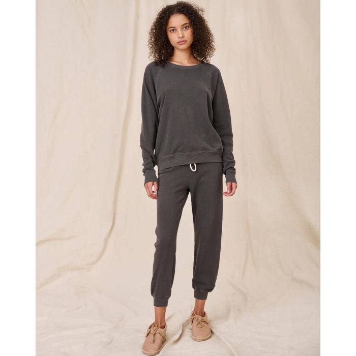 Sweatshirt College en coton noir délavé The Great, porté de face avec un bas de jogging Crop de la même couleur et de la même marque. 
