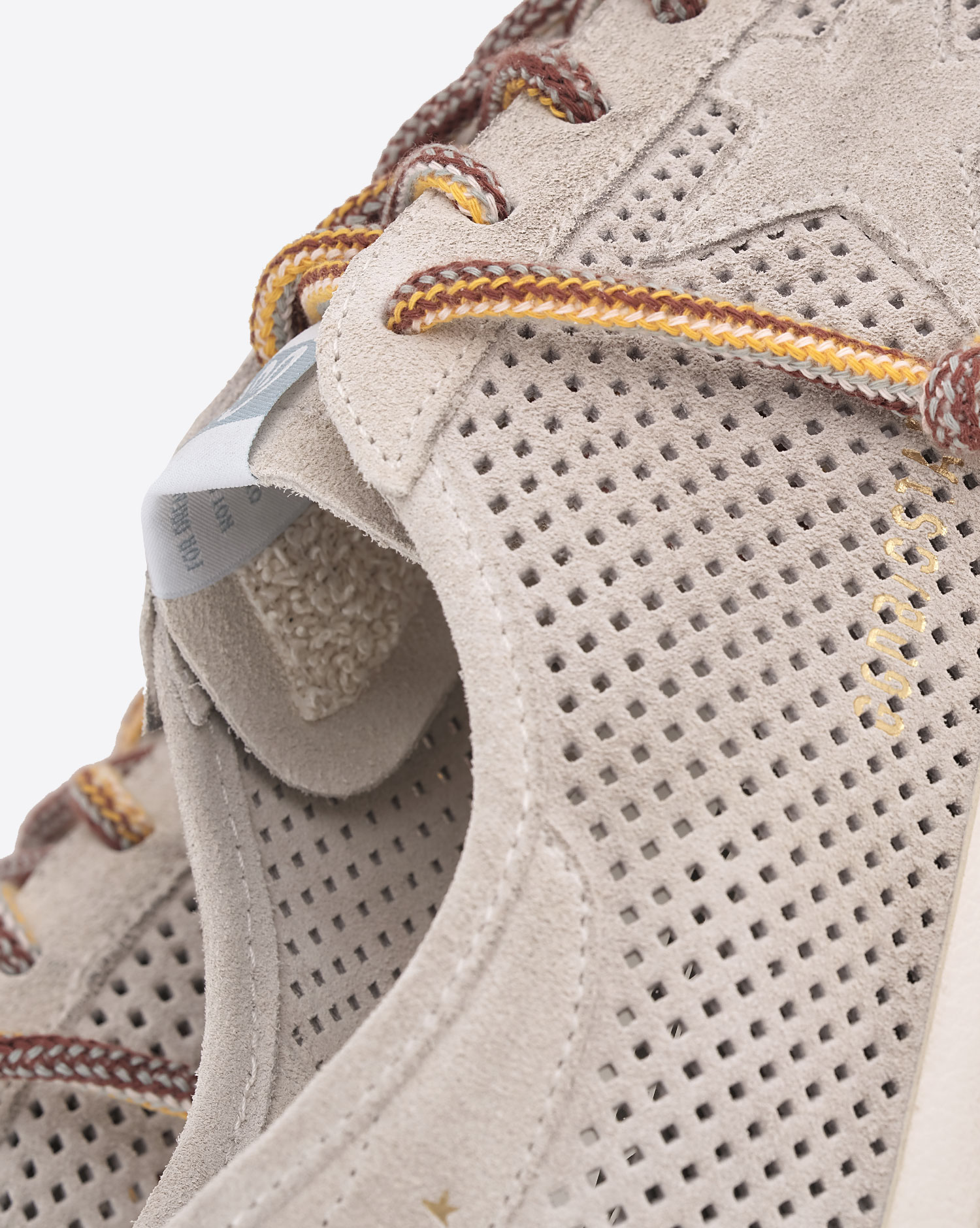Sneakers Super-Star Golden Goose en daim crème ajouré étoile ton sur ton. Détail des matière et lacets multicolores.