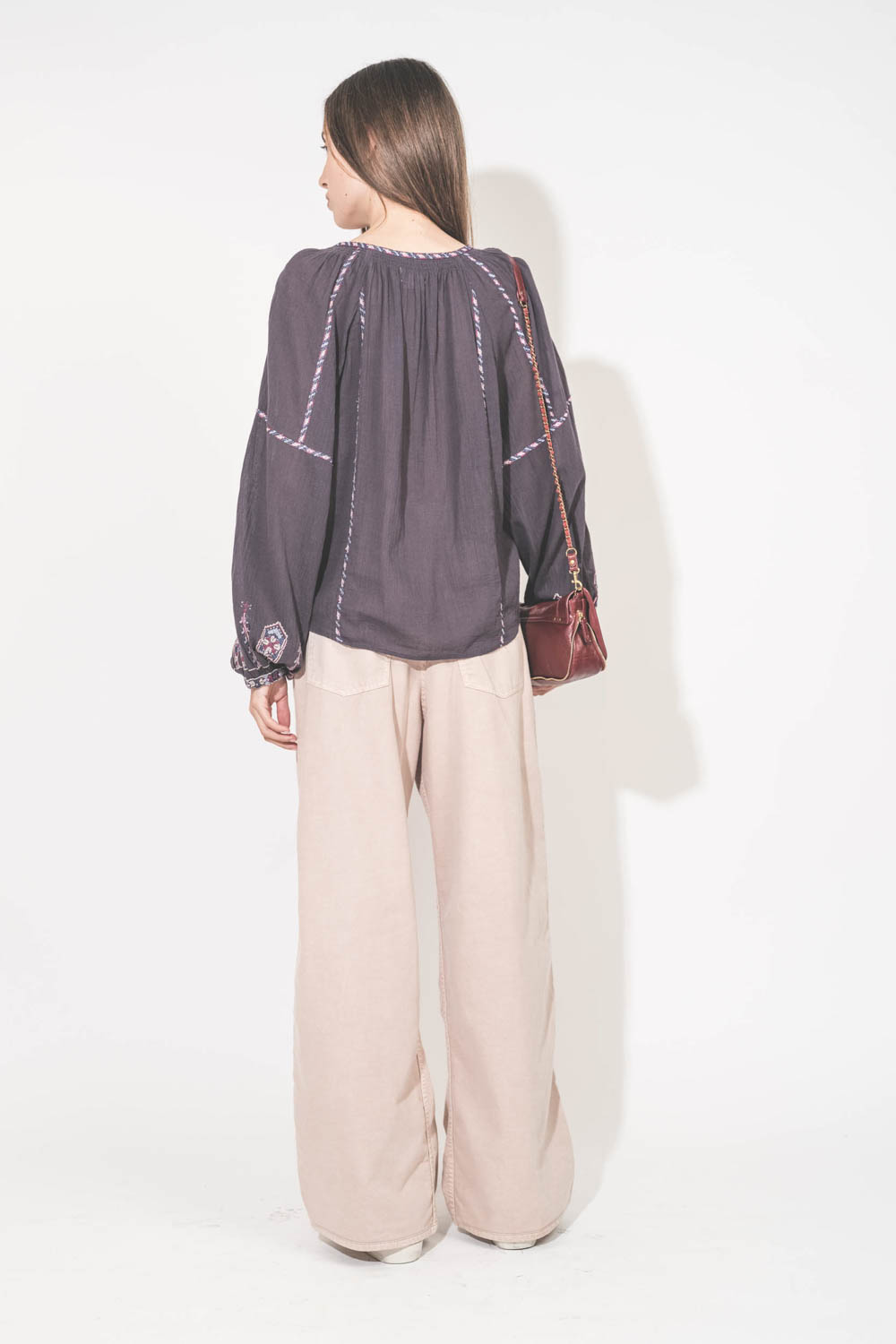 Jean large à pinces Twill 45 rose poudré Skin Candy Haikure. Porté de dos avec un top manches longues en voile de coton brodé bleu nuit lilas Fernanda Isabel Marant Etoile et des sneakers Super Star en cuir blanc languette rose Golden Goose. Sac Bobi S en