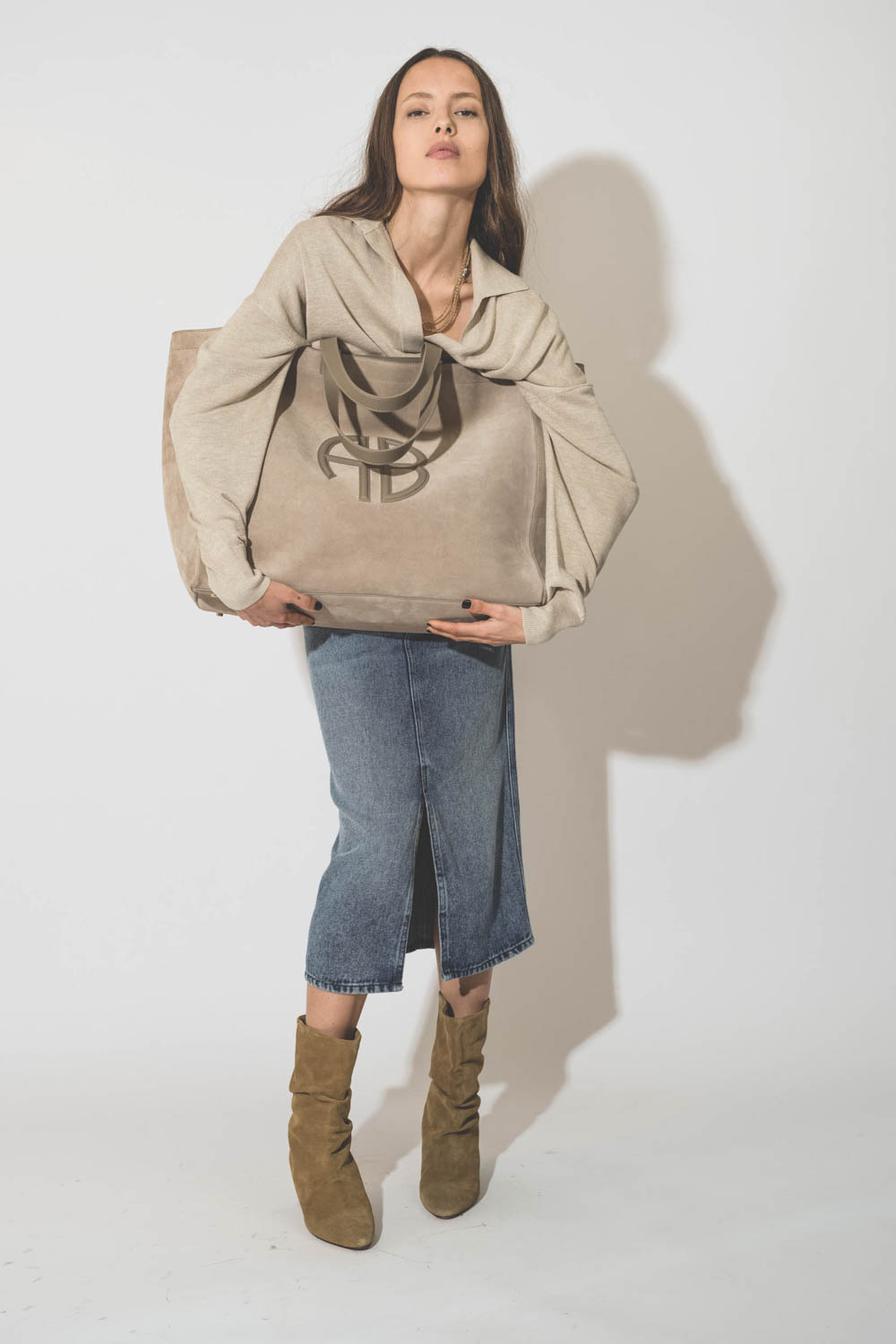 Boots à petits talons en cuir suédé taupe Reachi Isabel Marant. Porté avec un grand cabas en cuir beige.