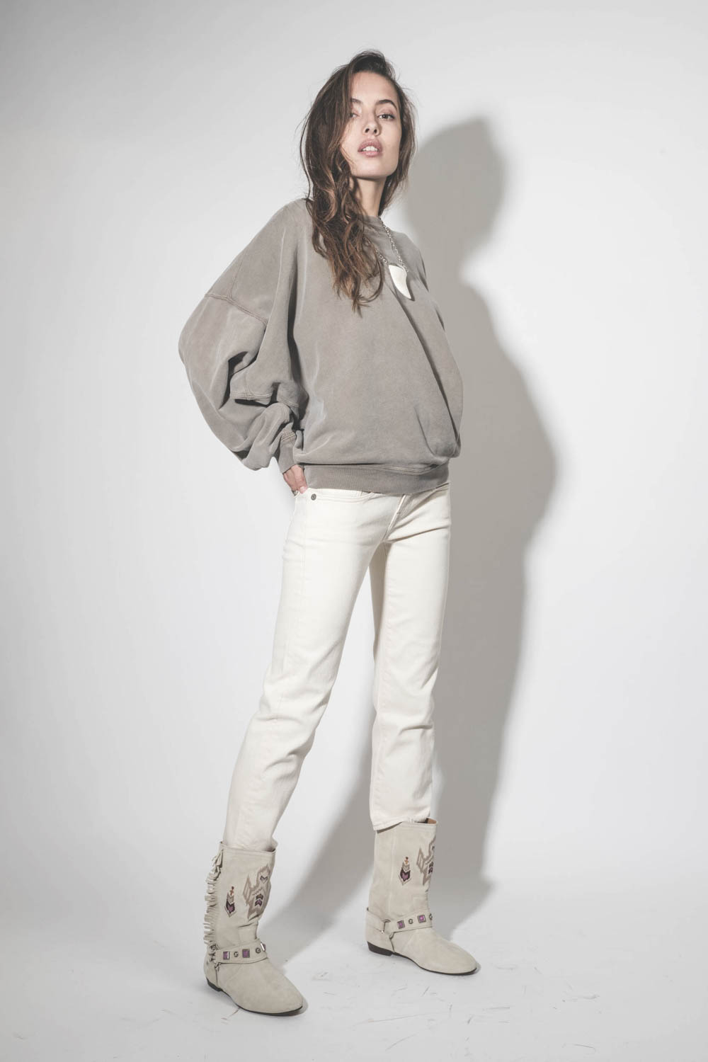 Bottes en cuir suédé écru brodées harnais et mini franges sur les côtés Siani Isabel Marant. Porté de profil.
