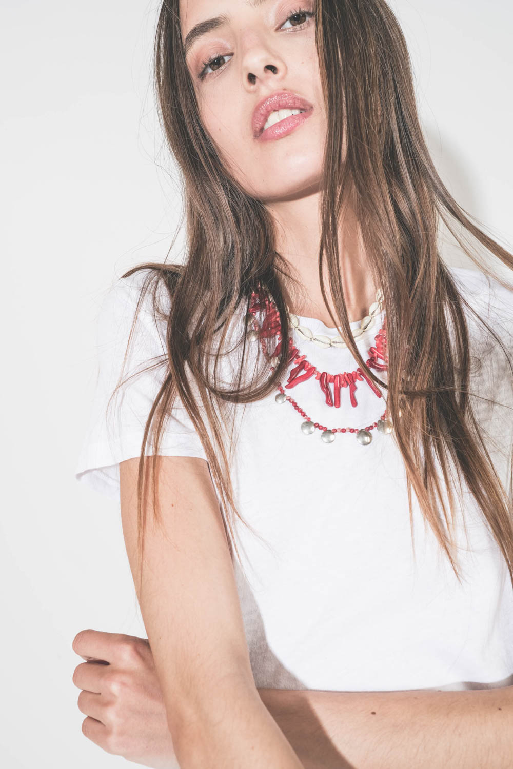 Collier pierres rouges et pampilles en métal argentés Isabel Marant. Porté de face en accumulation avec un collier coquillage Noki et un collier perles et os rouge Isabel Marant.