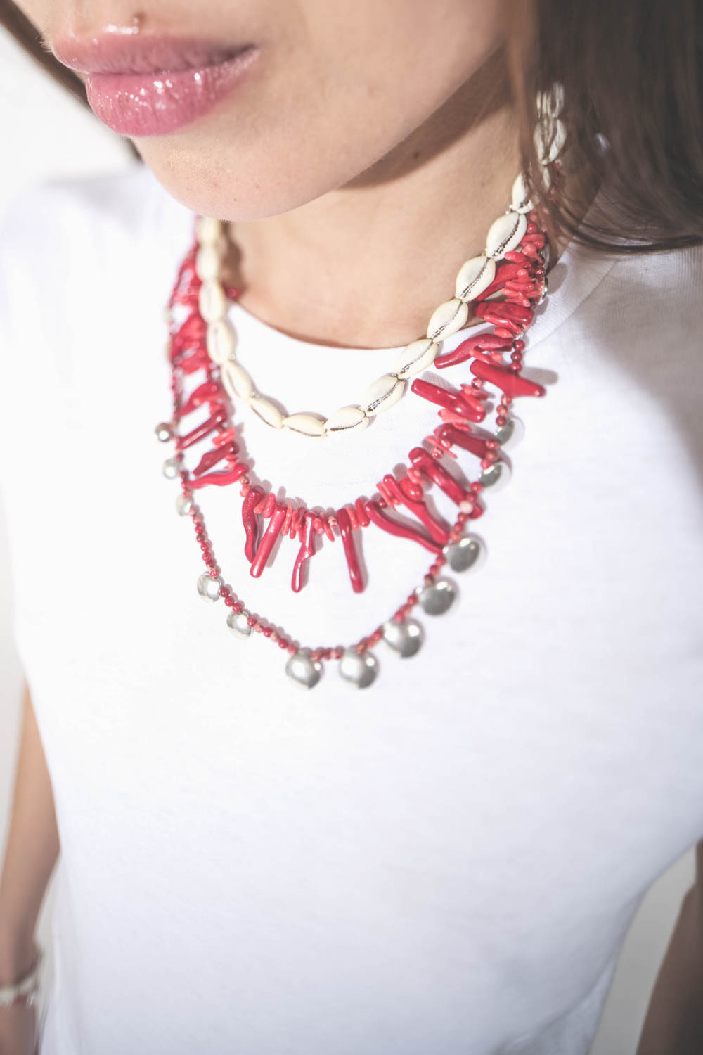 Collier de perles et os rouges Jolana Isabel Marant. Porté en accumulation avec un collier coquillage Noki et un collier Adriel en perles rouges et pampilles en métal argenté Isabel Marant. 