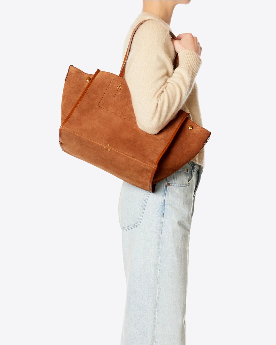 Sac cabas Léon M Jérôme Dreyfuss en cuir suédé caramel porté à l'épaule.