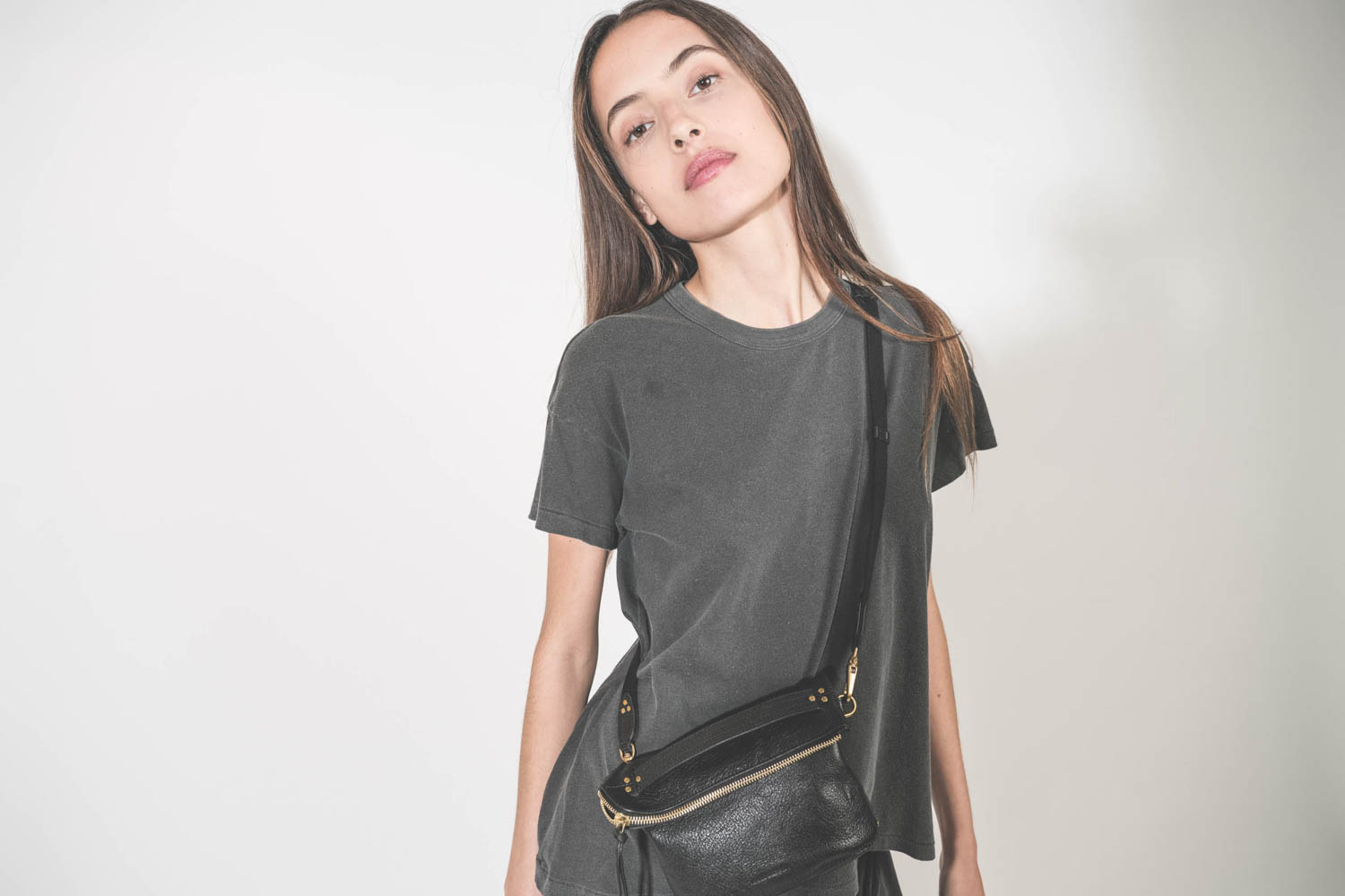 Pochette en cuir de chèvre noir grainé portée crossbody avec une bandoulière sangle large noire Jérôme Dreyfuss. Tee-shirt manches courtes Boxy Crew noir délavé The Great.