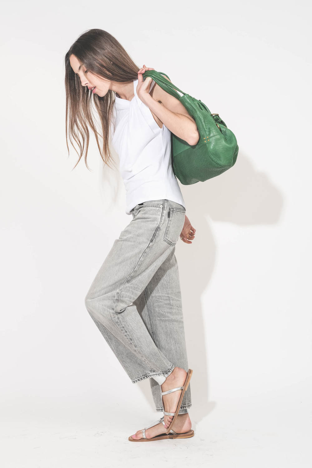 Sac forme cabas en cuir vert gazon Billy M Jérôme Dreyfuss. Porté main sur l'épaule avec un tee-shirt sans manches blanc Nayda Marant Etoile et un jean large gris Betty Haikure. Sandales plates en cuir argent Caravelle K.Jacques St-Tropez. Bagues Harpo en