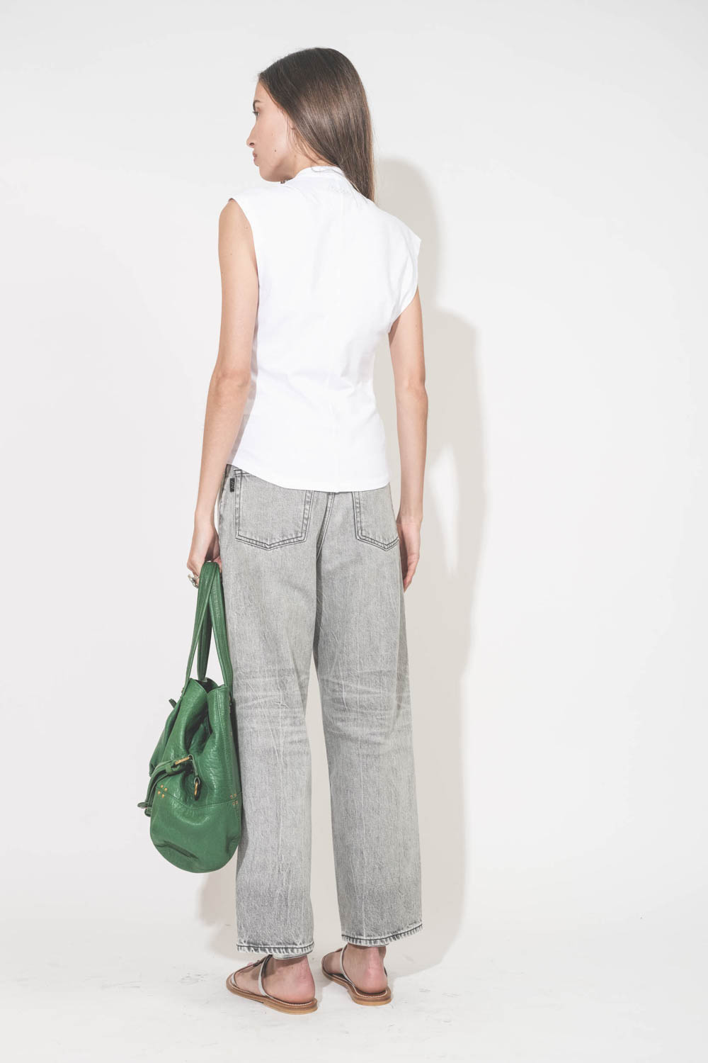 Sac forme cabas en cuir vert gazon Billy M Jérôme Dreyfuss. Porté main de dos avec un tee-shirt sans manches blanc Nayda Marant Etoile et un jean large gris Betty Haikure. Sandales plates en cuir argent Caravelle K.Jacques St-Tropez. Bagues Harpo en argen