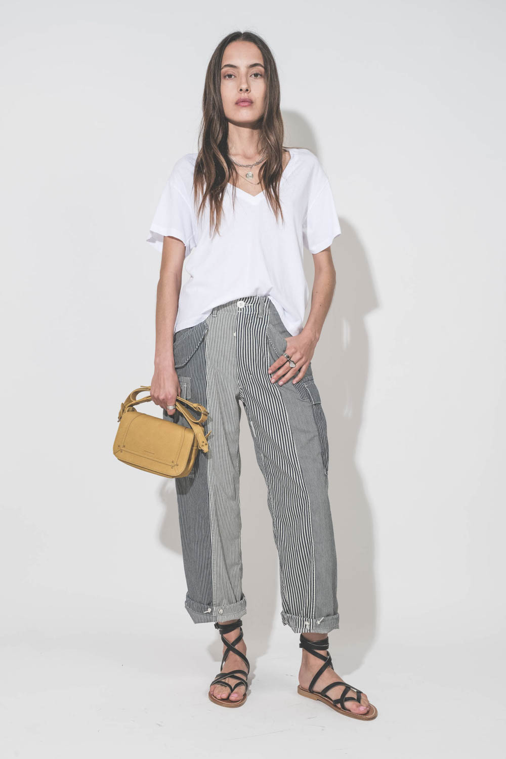 Sandales plates en cuir noir Zenobie K.Jacques Saint-Tropez. Portées avec un tee-shirt col V blanc The Great, un pantalon Cargo à rayures R13 denim et un sac en cuir jaune Mimosa Pepito S Jérôme Dreyfuss. Bague en argent Mikuta.
