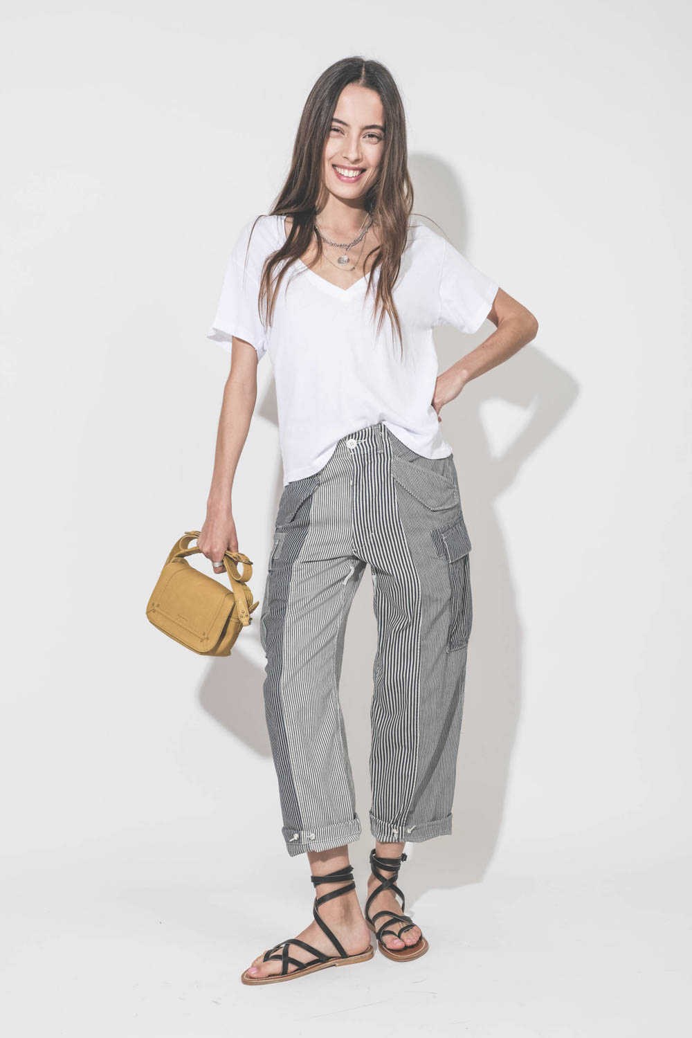 Sandales plates en cuir noir Zenobie K.Jacques Saint-Tropez. Portées avec un tee-shirt col V blanc The Great, un pantalon Cargo à rayures R13 denim et un sac en cuir jaune Mimosa Pepito S Jérôme Dreyfuss. Collier en argent Maria Black et Pascale Monvoisin