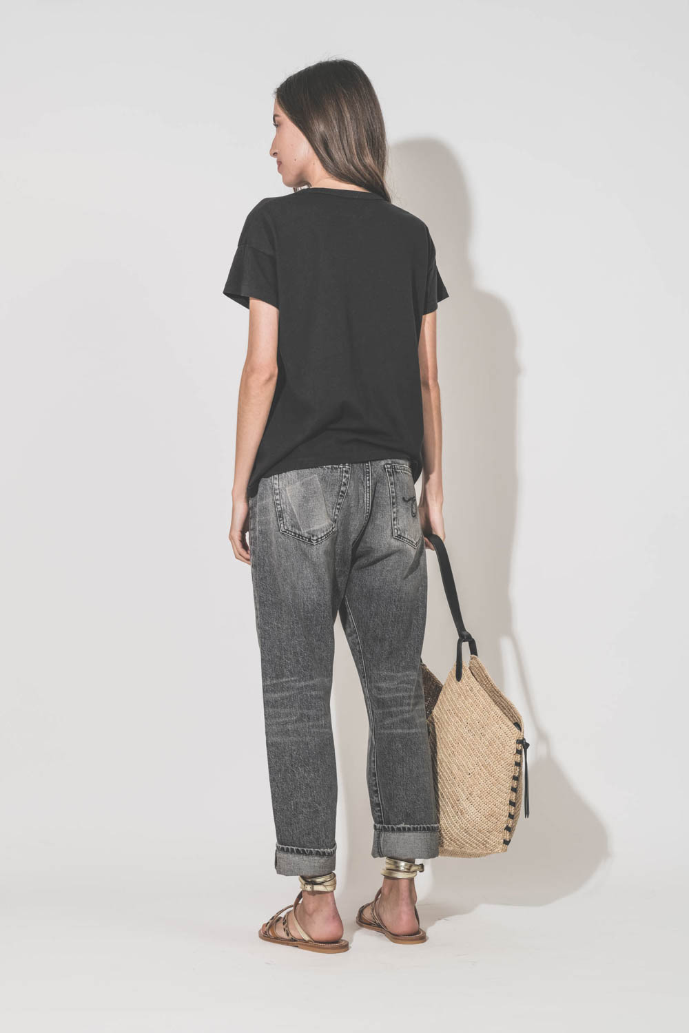 Sandales plates en cuir naturel, léopard et platine Zenobie K.Jacques Saint-Tropez. Porté de dos avec un tee-shirt noir manches courtes Boxy Crew The Great et un jean Crossover Leyton black R13 Denim. Ceinture en cuir noir Dara Isabel Marant et panier en 