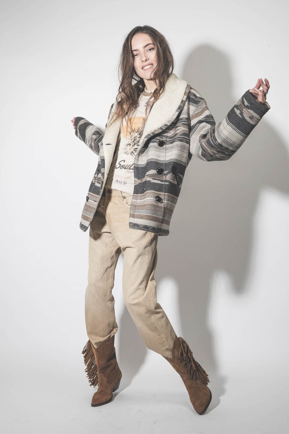 Manteau col châle fausse fourrure en laine motifs graphiques beige et écru Dorcas Marant Etoile.  Porté avec des boots à franges.