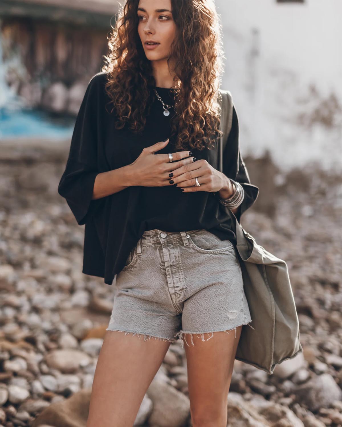 Tee-shirt manches courte épaule basse en coton noir oversize Mikuta. Porté avec un short en jean kaki Mikuta et des bijoux en argent Mikuta.  