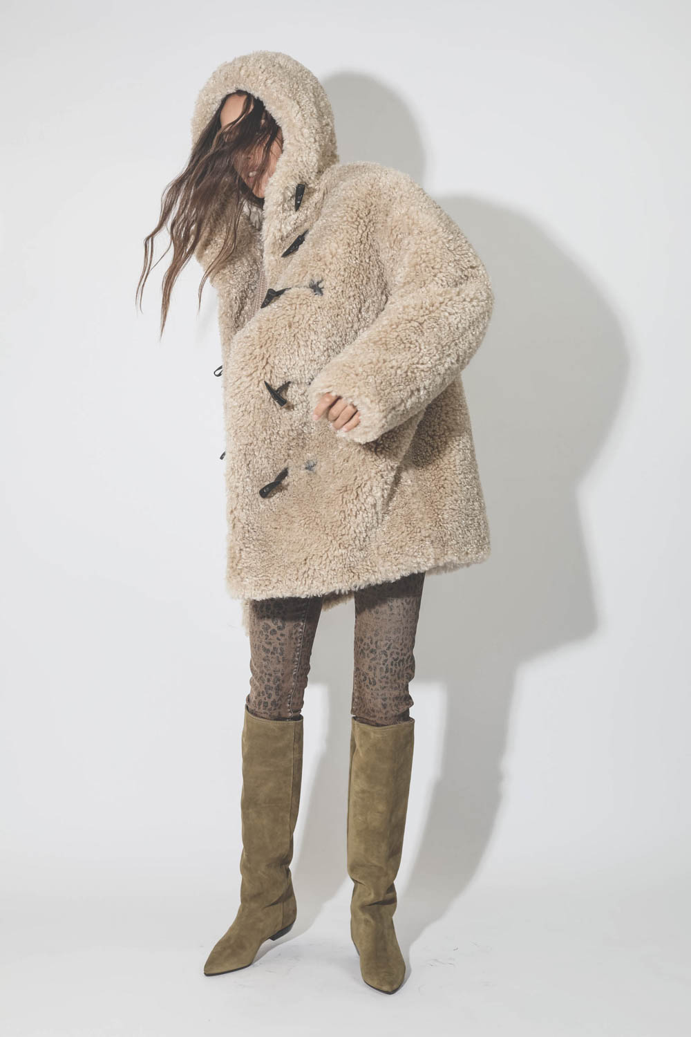 Manteau 3/4 à capuche en fausse fourrure beige Florene Marant Etoile. Porté avec des bottes en cuir suédé beige.