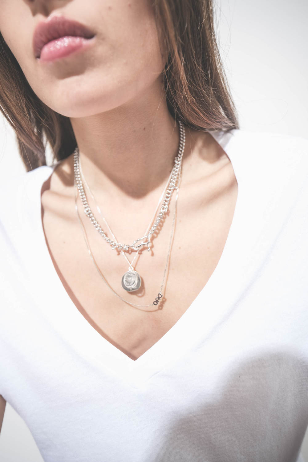 Collier en argent chaine avec une médaille en argent gravée "GB.03" et pavée de diamants et une médaille en cristal de roche gravée "AMOUR" Pascale Monvoisin. Porté en accumulation avec un collier chaine en argent Berline Maria Black et un collier chaine 