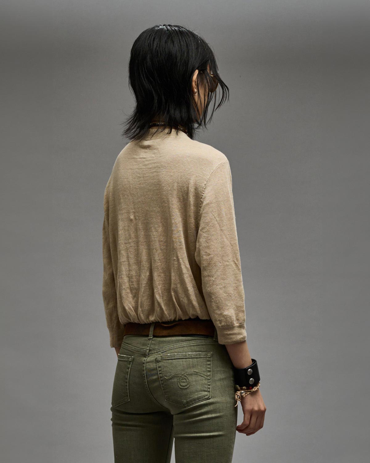 Gilet manches longues court en lin beige Balloon Cardigan R13. Porté profil dos.