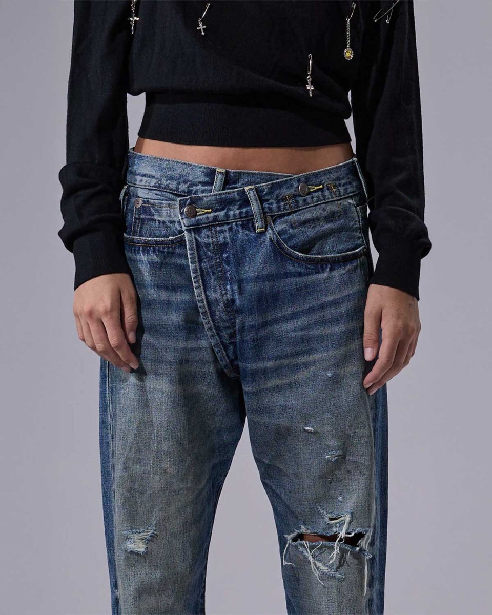 Jean crossover R13 en denim bleu déchiré Léo Blue. Détails du délavage et de la fermeture croisée.