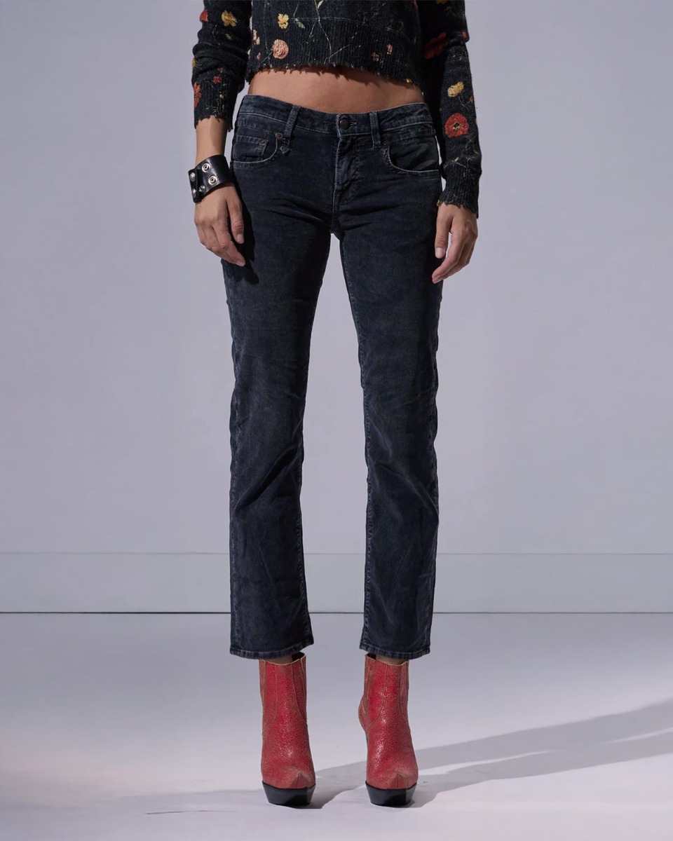 Jean slim taille basse Boy Straight R13 en velours de coton côtelé noir délavé Obsidian Stretch Cord Black, porté de face avec des boots à talons.