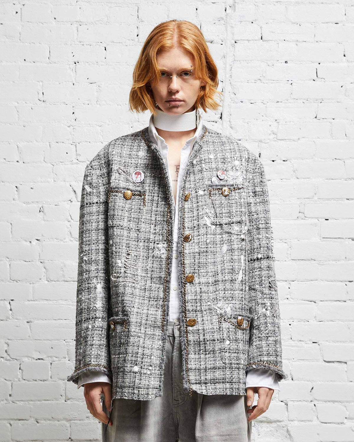 Veste oversized en tweed gris et taches de peinture avec des chaines, épingles à nourrice et badges R13. Porté de face. 