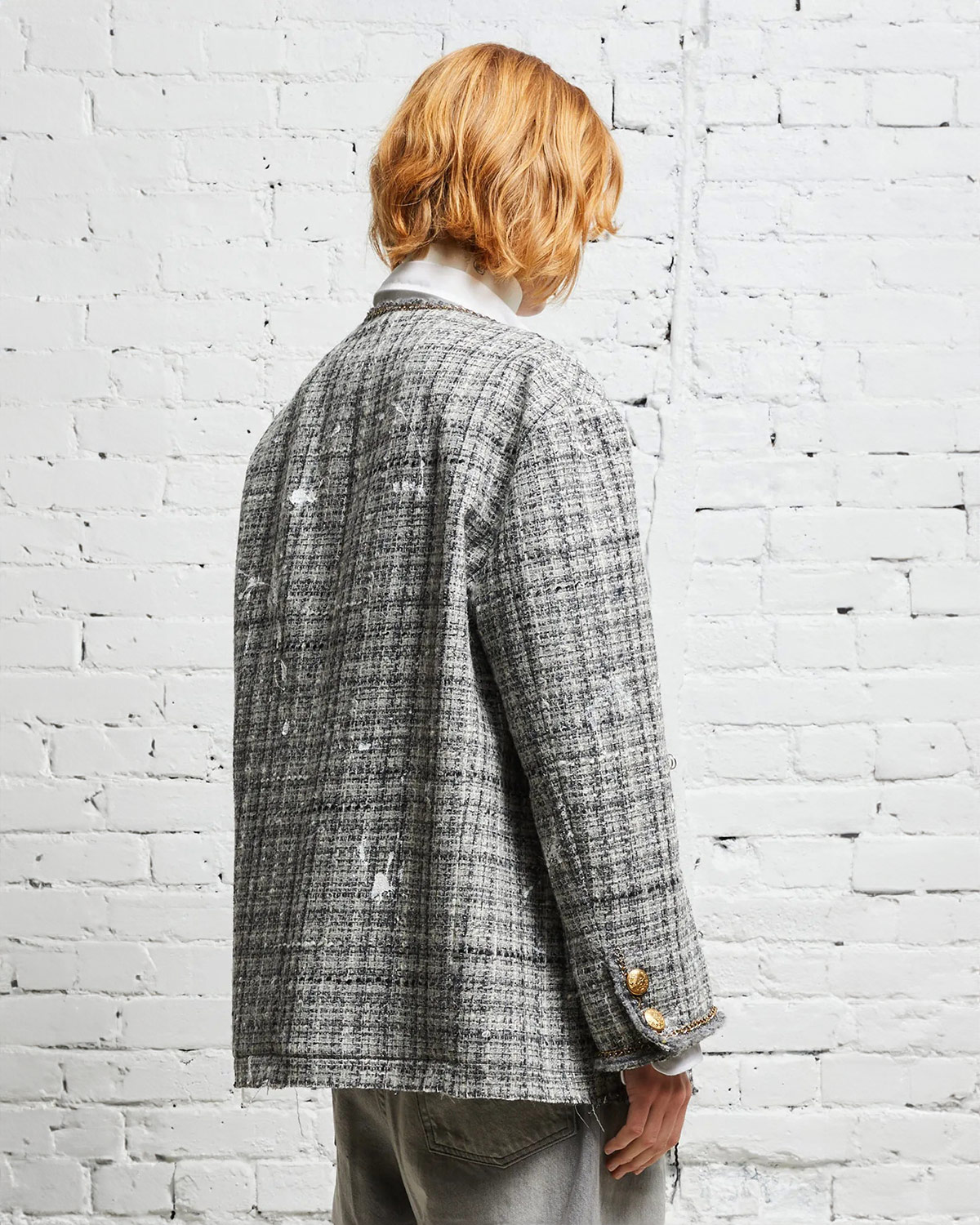 Veste oversized en tweed gris et taches de peinture avec des chaines, épingles à nourrice et badges R13. Porté de dos de profil.