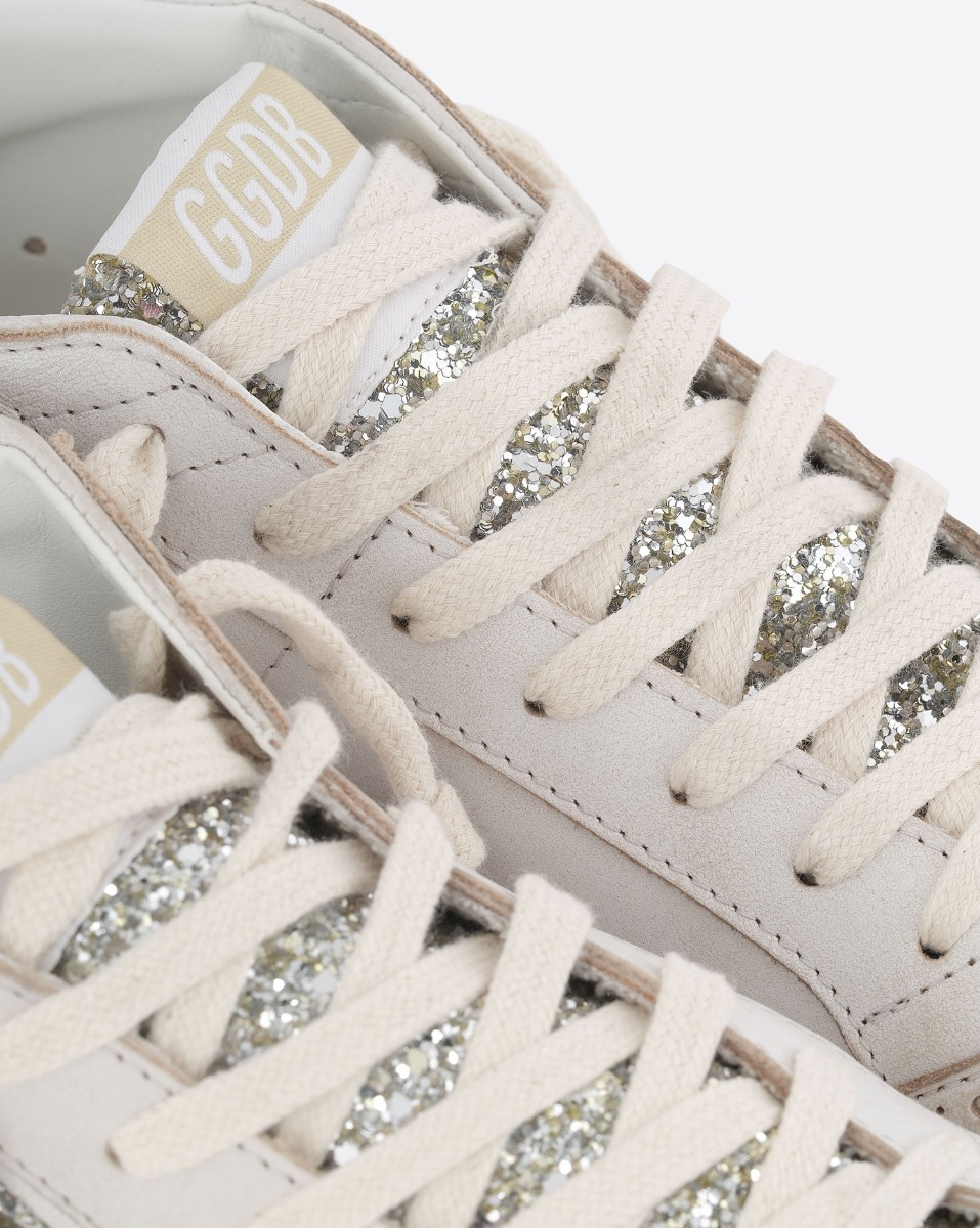 Sneakers Mid Star Golden Goose en cuir blanc, étoile et languette à paillettes argent. Détail des lacets et de la languette à paillettes argentées.