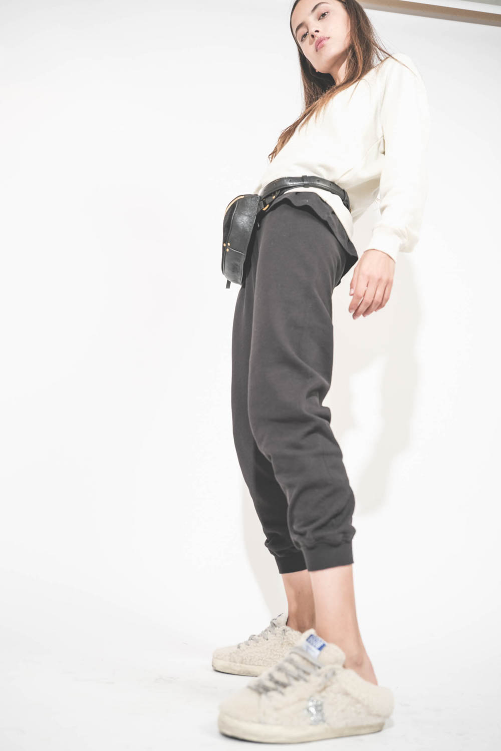 Pantalon de jogging taille basse à nouer sur les hanches resserré en bas bord côte noir The Cropped Sweatpant The Great. Porté avec un sweat-shirt manches longues Shrunken écru The Great et des sneakers Super Star sabot en fourrure écru 10757 Golden Goose