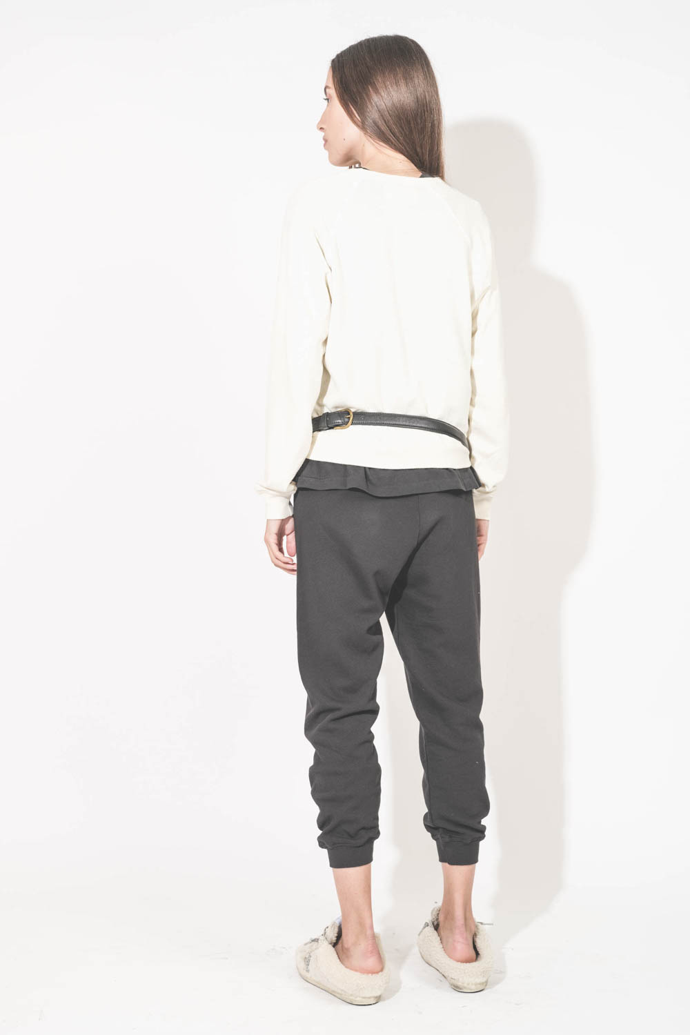 Pantalon de jogging taille basse à nouer sur les hanches resserré en bas bord côte noir The Cropped Sweatpant The Great. Porté de dos avec un sweat-shirt Shrunken écru The Great et des sneakers Super Star sabot en fourrure écru 10757 Golden Goose. Sac lin