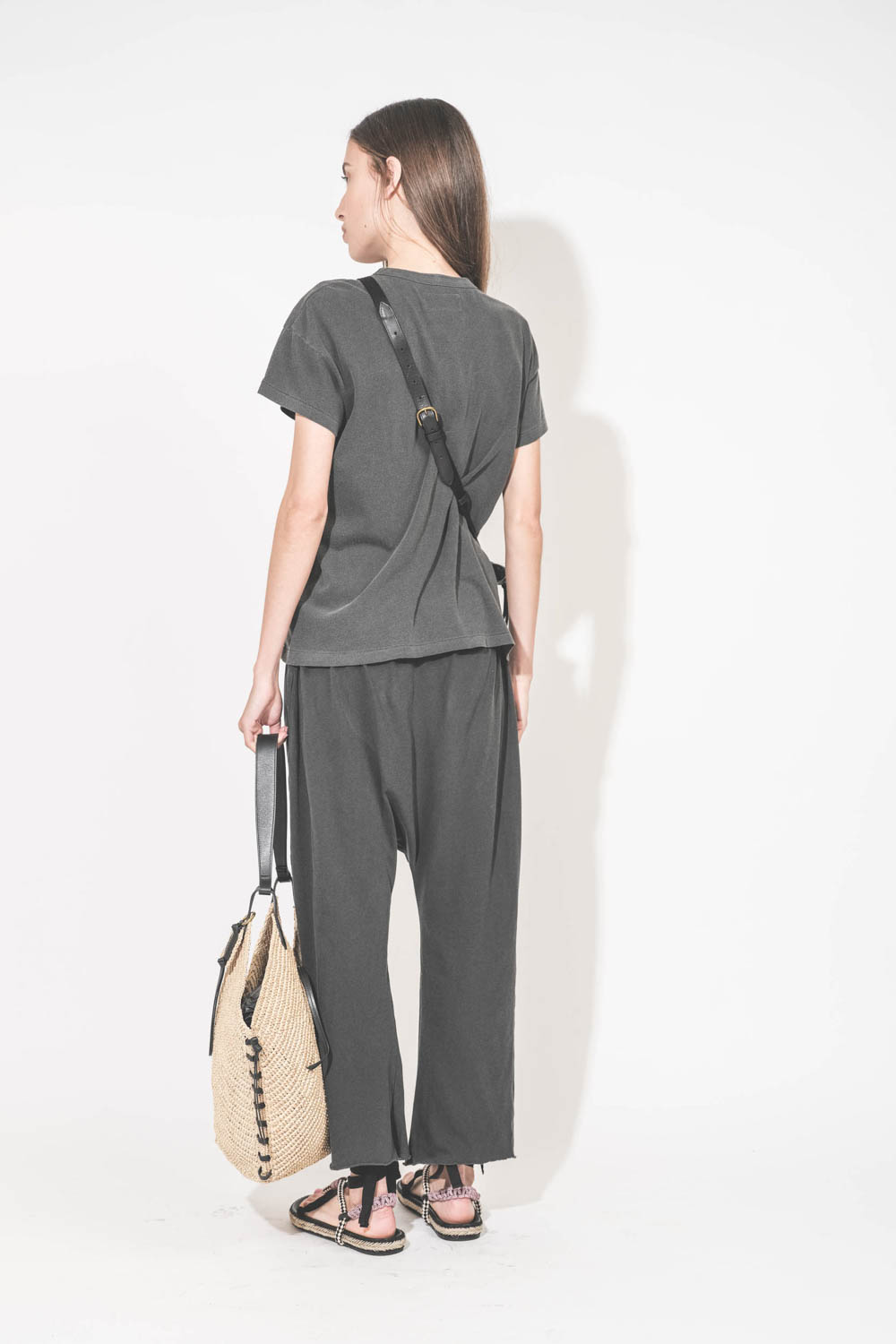 Pantalon sarouel court en jersey noir délavé The Great. Porté de dos avec un tee-shirt manches courtes noir délavé Boxy Crew The Great et des sandales en cordes tressées avec ruban Gypsa noir Isabel Marant. Pochette Lucky en cuir noir avec une bandoulière