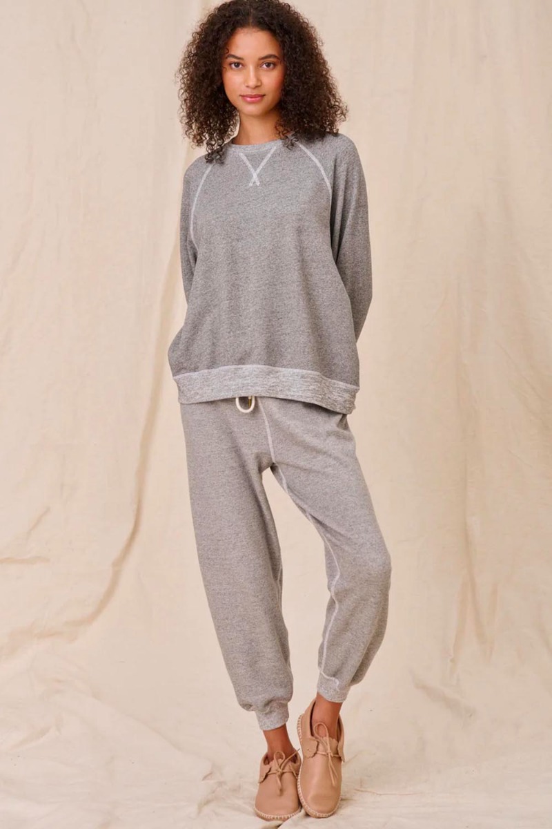 Sweatshirt encolure ronde en coton mélangé gris chiné surpiqures blanches The Slouch Sweatshirt The Great. Porté de face avec un bas de jogging assorti The Great. 