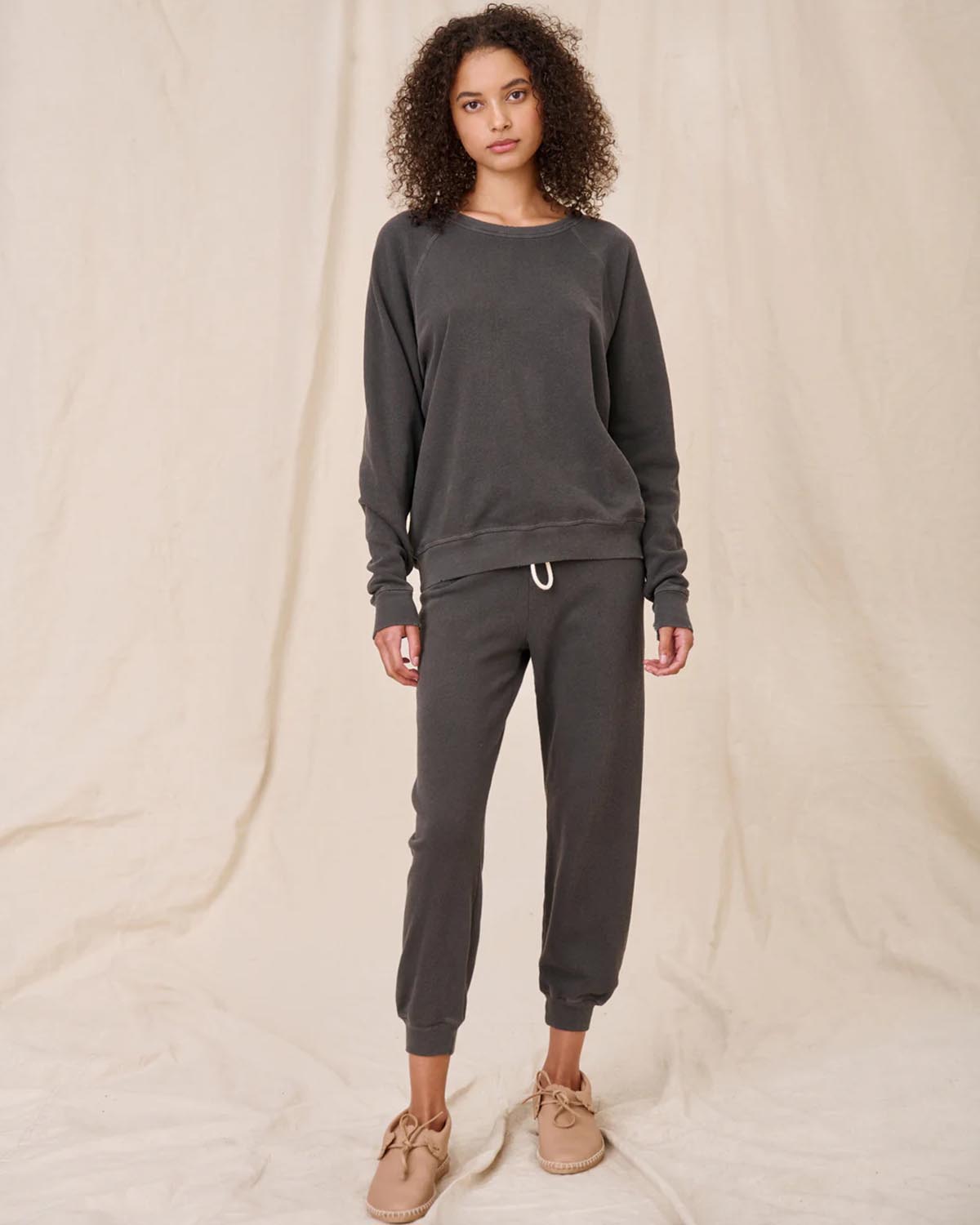 Sweatshirt College en coton noir délavé The Great, porté de face avec un bas de jogging Crop de la même couleur et de la même marque. 
